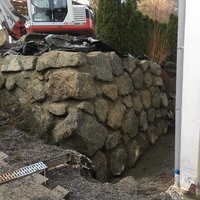 Bagger auf Steinmauer