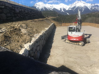 Bagger vor einer Steinmauer